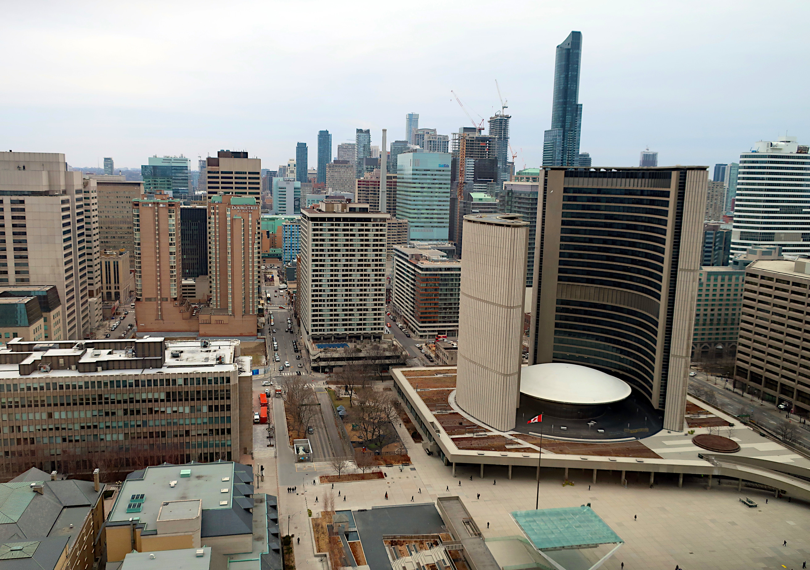Das neue Rathaus von Toronto, von schräg oben fotografiert, umgeben von anderen Gebäuden. Blätterlose Bäume deuten auf winterliche Jahreszeit hin, aber es liegt kein Schnee.