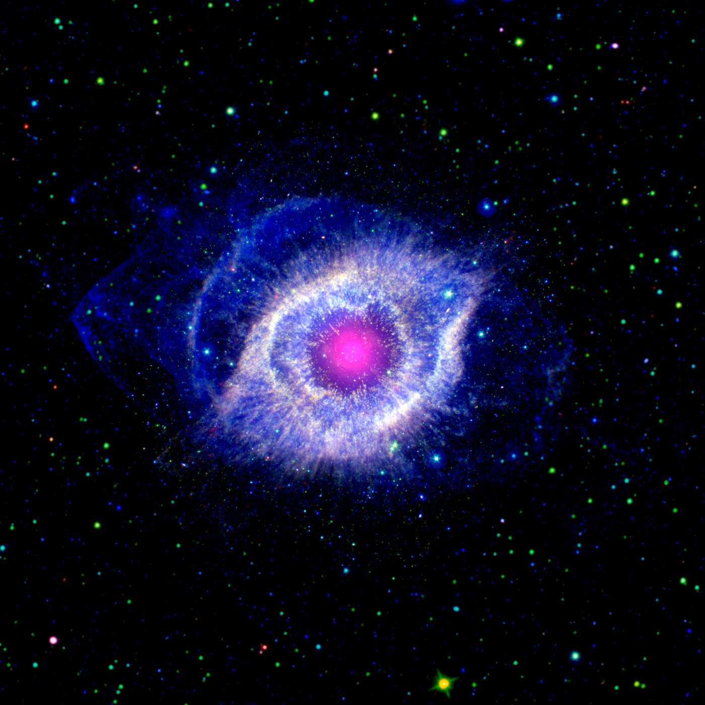Ein Foto von NGC 7293, auch als Helixnebel bekannt. Der Nebel sieht von der Erde aus wie ein riesiges blau-weißes Auge, das von leuchtend blauen Wolken umgeben ist. Den Hintergrund bildet das schwarze Weltall, gesprenkelt mit unzähligen, teilweise recht großen, grün-blauen Sternen. Im Inneren des Auges leuchtet wie eine Pupille kreisförmig ein rosafarbener Nebel.